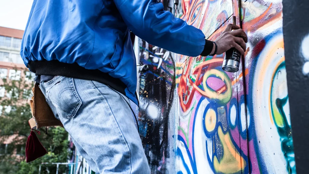 person som målar grafitti på utomhusvägg